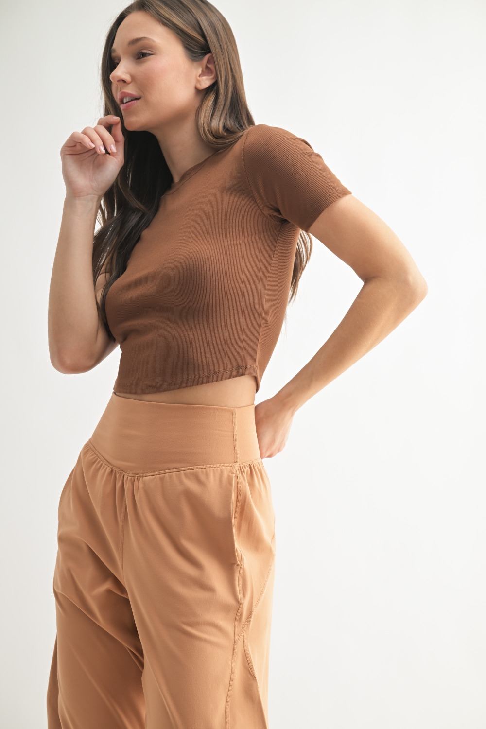 Woman wearing fitted black micro-ribbed cropped baby tee with short sleeves and round neckline.